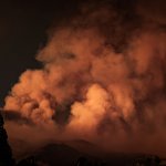 A large plume of smoke rising from a forest