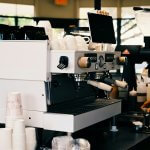 Barista preparing coffee with espresso machine in cafe.