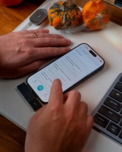 Person using smartphone with keyboard and pumpkins